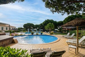 Une piscine avec des chaises longues et un kiosque.