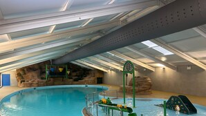 An indoor swimming pool with a slide, a rock wall, and a ceiling with skylights. - Perfect Seaside Escape, Wifi Heated Indoor Pool Bar & Facilities near to St Ives (Lelant)