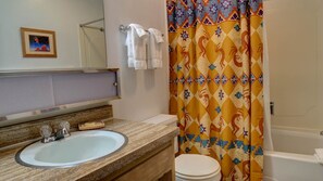 A bathroom with a sink, mirror, and a shower curtain with a geometric pattern. - Cozy Condo close to the Chair Lift (Angel Fire)