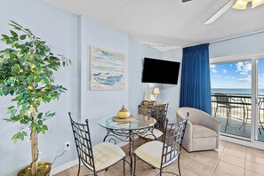 Enjoy ocean views from the large windows in this spacious living area, featuring a seating area, flat-screen TV, and decorative plant.