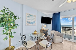Enjoy ocean views from the large windows in this spacious living area, featuring a seating area, flat-screen TV, and decorative plant.