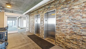 Un espace moderne pour les ascenseurs, avec un mur en briques à texture et deux ascenseurs.