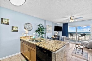 Enjoy ocean views from the kitchen's large window, adjacent to a dining area with a round table and chairs.