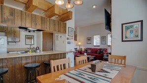 A kitchen with wooden cabinets, a bar area, and a dining table with stools.