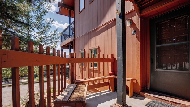 A wooden deck with benches, a metal railing, and a building with a garage door.