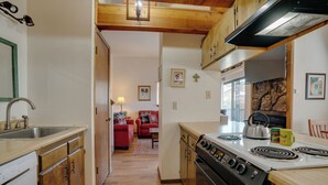 A compact kitchen with wooden cabinets, a stove, and a sink.