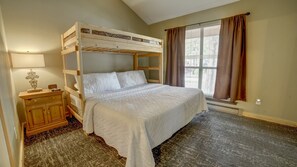 Habitación con literas, una mesita de noche de madera, una lámpara y una ventana con cortinas.