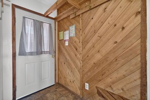 Un mur intérieur en bois avec une porte, une fenêtre avec des rideaux et une prise électrique fixée au mur.