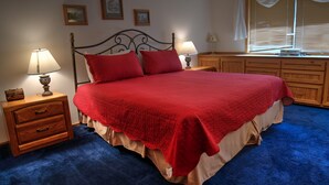 Une chambre à coucher avec un grand lit, des tables de chevet en bois, une commode et une fenêtre avec des stores.