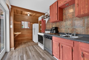 Una cocina con paredes de madera, un refrigerador, una estufa y un lavamanos.