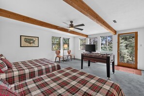 A room with two beds, a ceiling fan, a television, and a foosball table. - Home with Great Views of the Angel Fire Ski Mountain and Valley (Angel Fire)