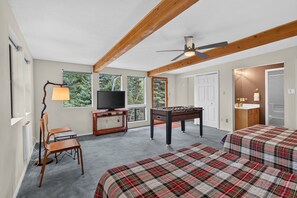 Ein Zimmer mit Fernseher, Kicker, zwei Betten mit karierter Bettwäsche, einem Schreibtisch und einem Stuhl.