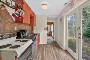 A kitchen with a stove, coffee maker, and red cabinets.