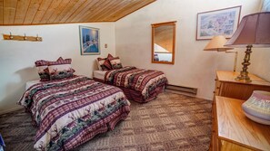 A bedroom with two beds, a wooden ceiling, a mirror, and a lamp. - Condo two blocks from the Chile Express (Angel Fire)