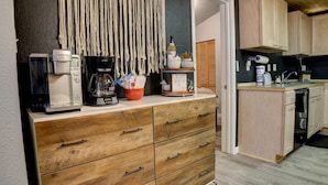 A kitchenette with a coffee maker, a blender, a kettle, and a small shelf with kitchen essentials.