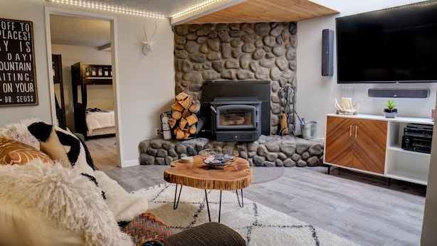 A cozy living room with a stone wall, a fireplace, a TV, and a wooden cabinet.