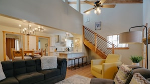 A spacious living area with a dark grey sofa, a yellow armchair, and a staircase leading to an upper level.