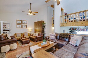 A spacious living room with leather sofas, a wooden coffee table, and a ceiling fan. - Townhome close to the base area (Angel Fire)