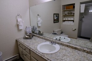 A bathroom with a granite countertop, two sinks, a toilet, and a shower. - Townhome close to the base area (Angel Fire)