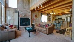 Un salón amplio con chimenea, sofás de cuero, una mesa de centro y un comedor con sillas y una mesa.