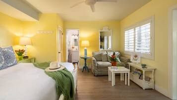 A hotel room with a bed, a desk, a chair, a mirror, and a window with blinds.