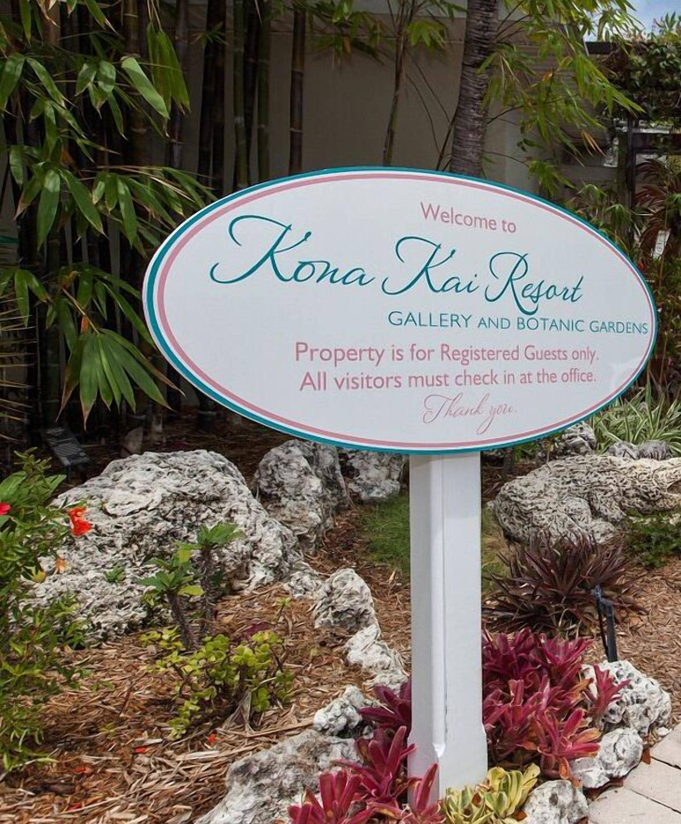 A sign welcoming visitors to Kona Kai Resort, indicating it is a property for registered guests only with a requirement to check in at the office.