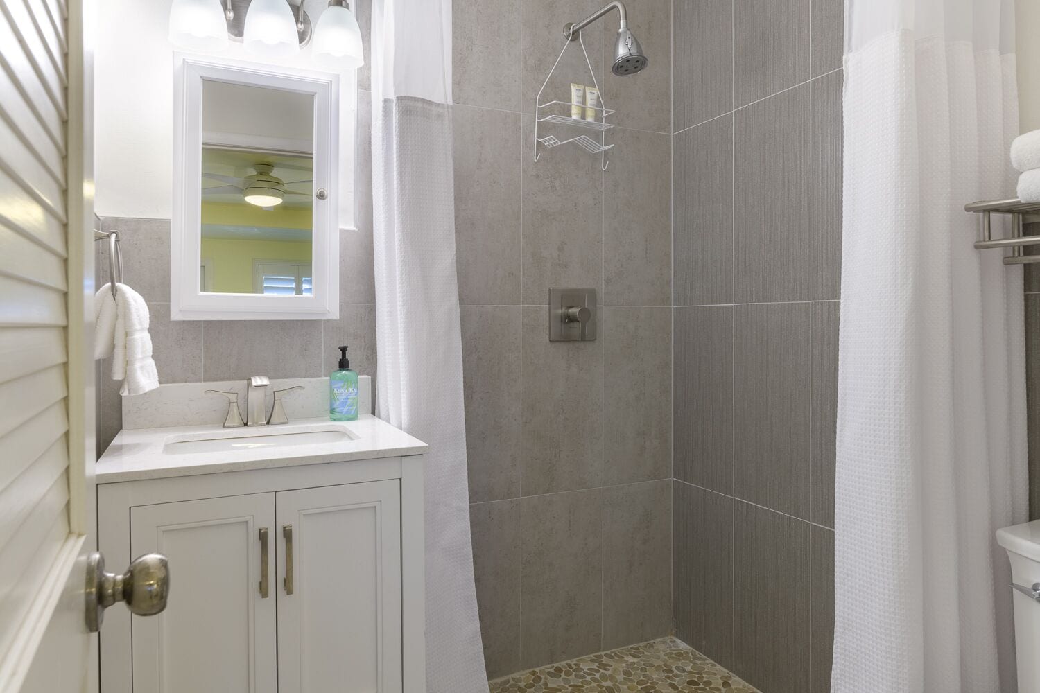 A bathroom with a shower, a sink with a mirror, and a towel rack.