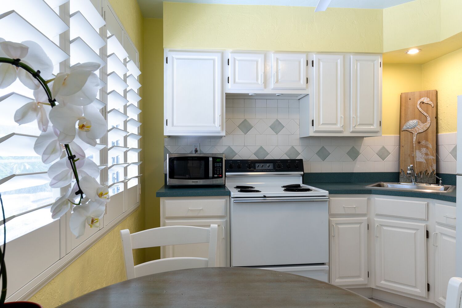 A kitchen with white cabinets, a microwave, a stove, and a sink.