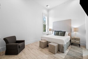 A bedroom with a bed, nightstands, a chair, and a window with blinds.