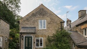 Une petite maison en pierre avec une porte verte, une petite fenêtre et une enseigne indiquant « Hope Cottage ».