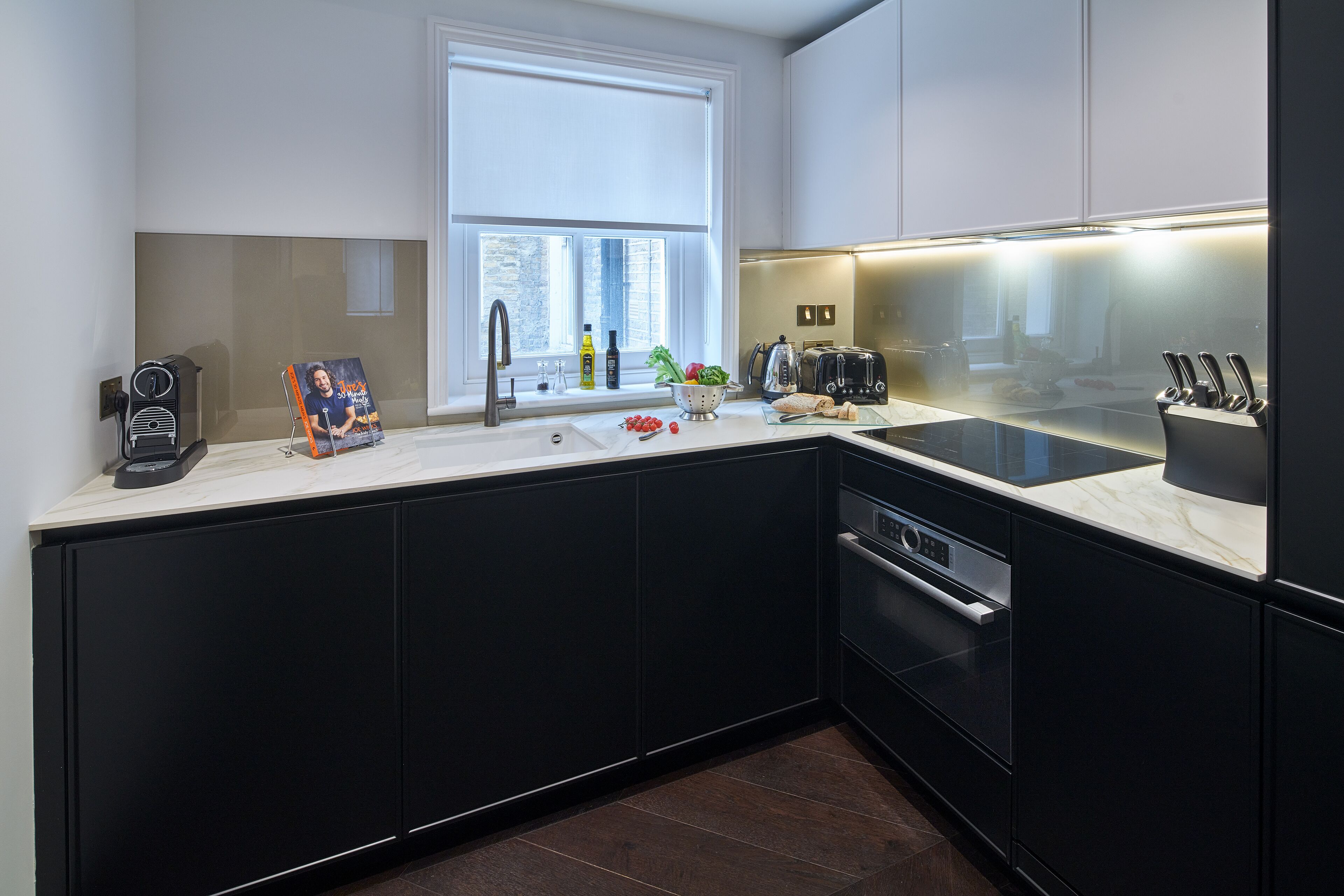 A modern kitchen with black cabinets, a window, a sink, a stove, and a countertop with various items.