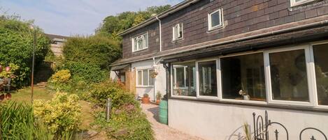 Une maison à deux étages avec un jardin à l’avant.