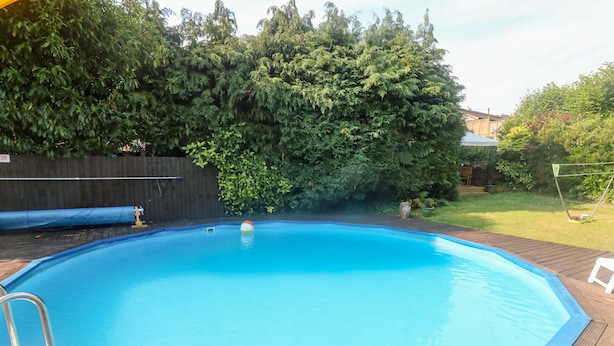 A rectangular swimming pool with a wooden deck surrounding it. - Honeysuckle Cottage (Paignton)
