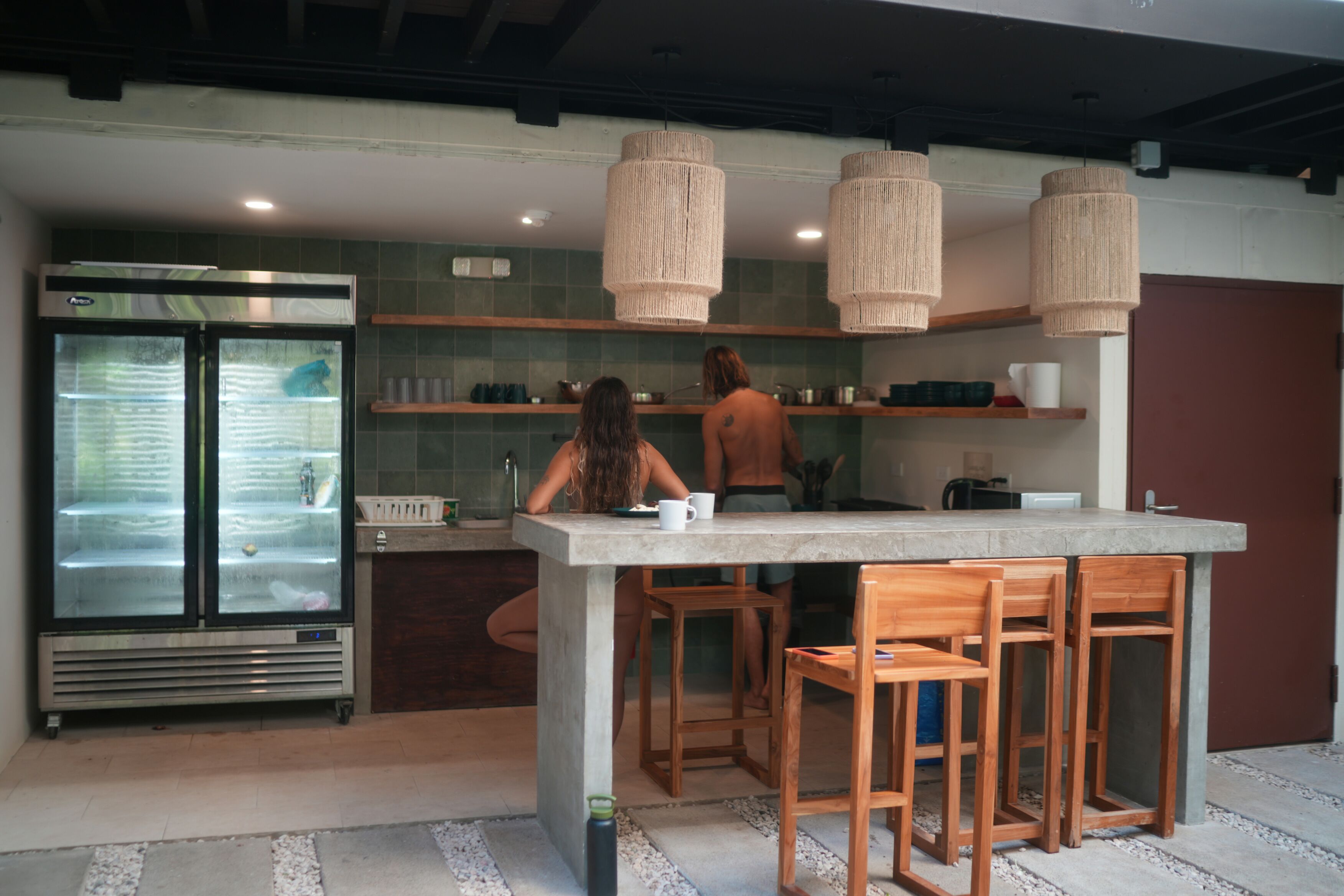 Une cuisine moderne dotée d’un grand îlot central, de tabourets de bar en bois et d’un réfrigérateur encastré.