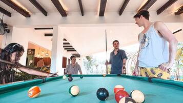 A pool table with balls, a ceiling with wooden beams, and a room with a view of the outdoors.