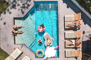 Vista aérea de uma piscina com várias pessoas e cadeiras de sol.