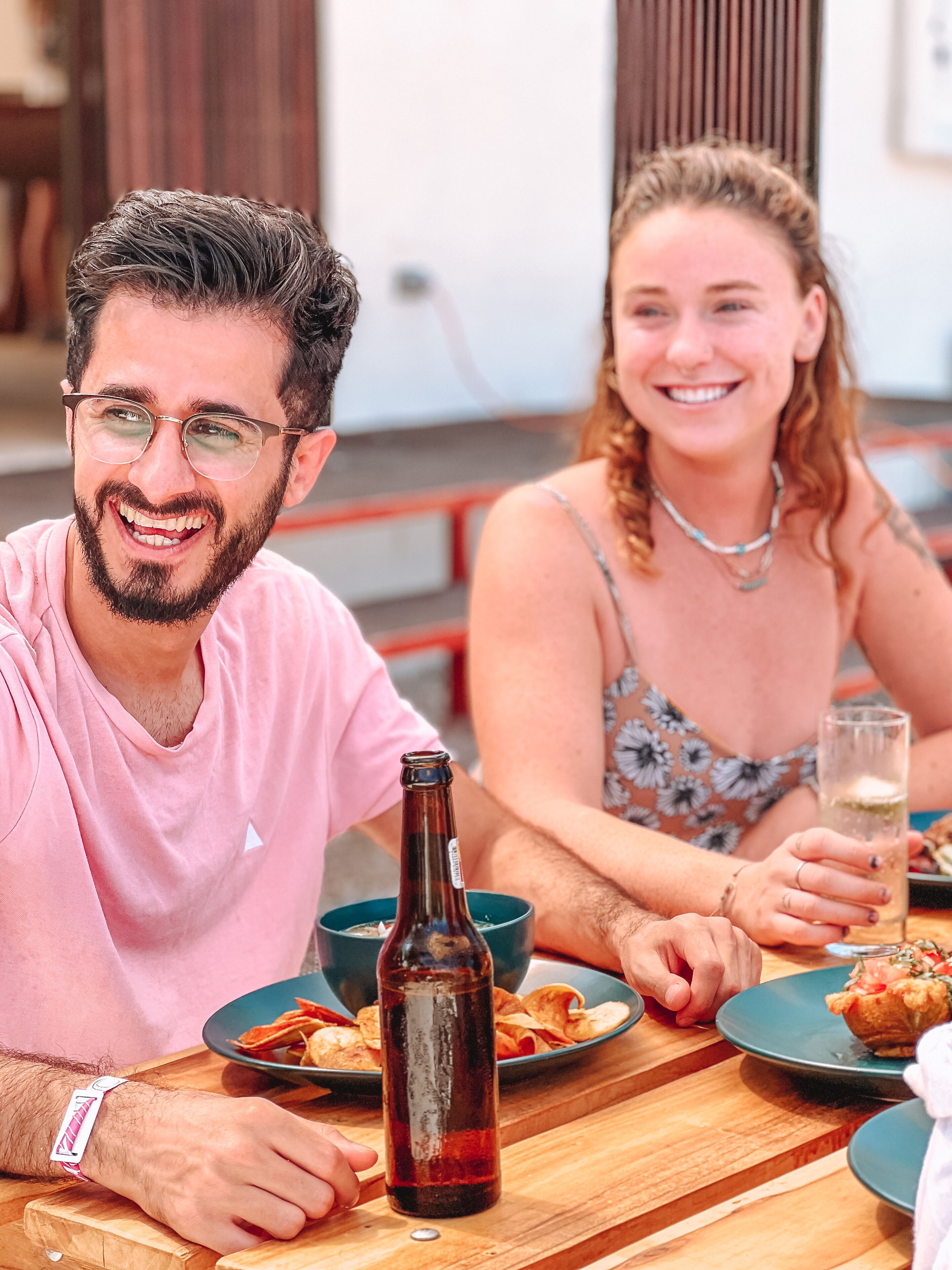 A wooden table with plates of food, a bottle, and a glass.