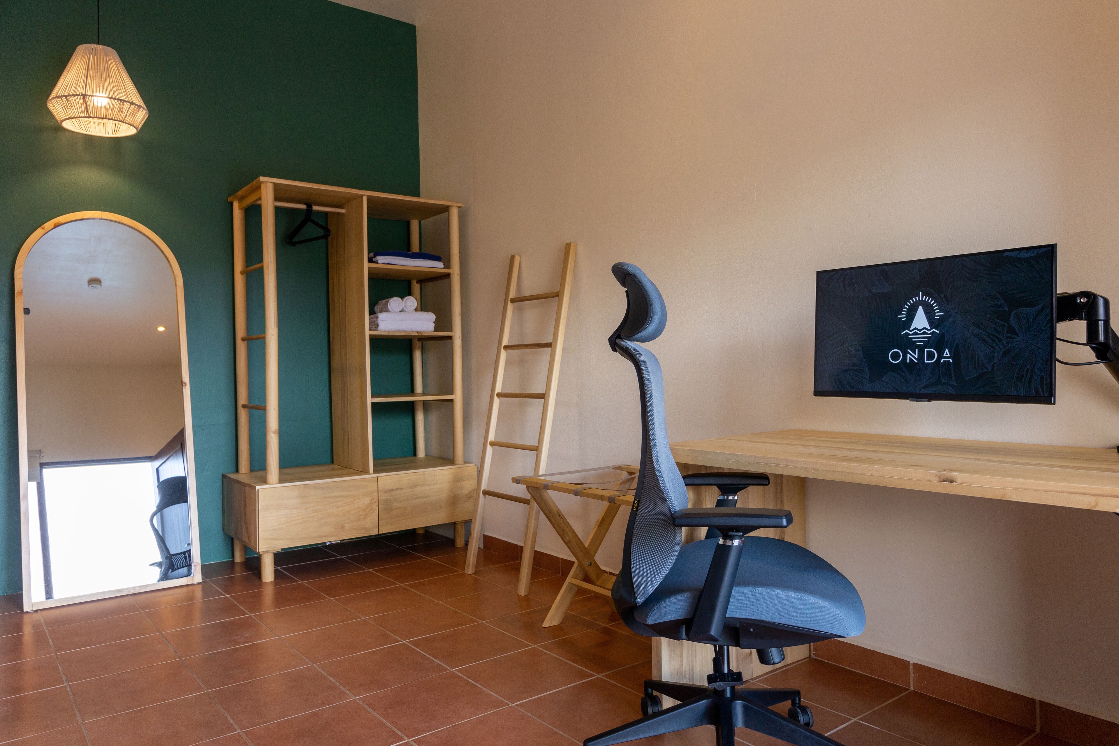 A room with a desk, chair, wardrobe, and a TV screen displaying the ONDA logo.