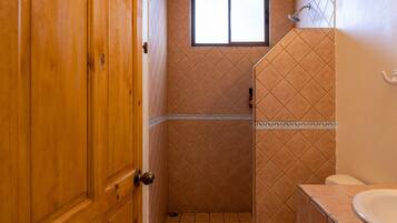 Un baño con puerta de madera, ventana, ducha y retrete.