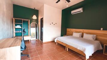 A bedroom with a bed, desk, chair, and an air conditioning unit.