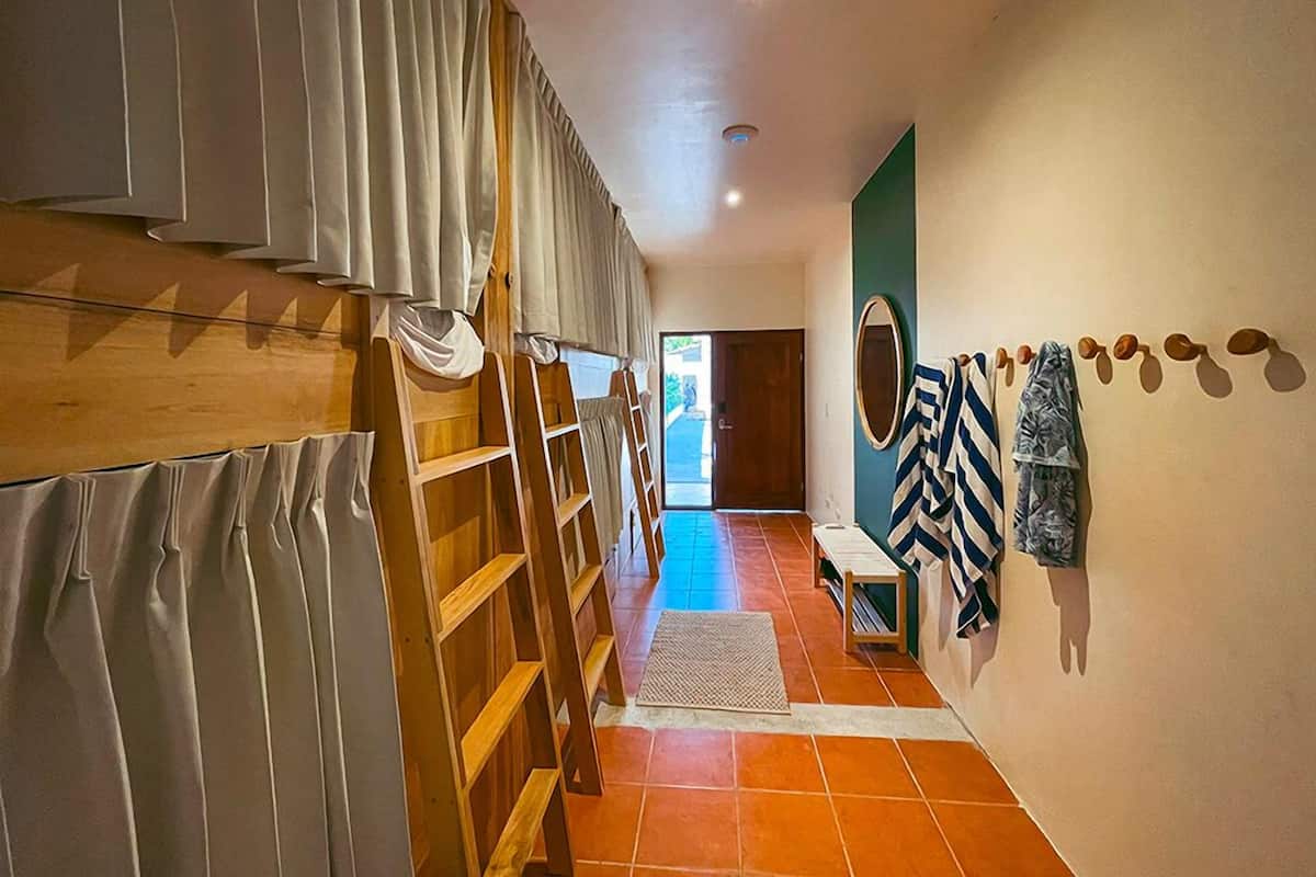 A hallway with a wooden ladder, a bench, and a wall with hanging towels.