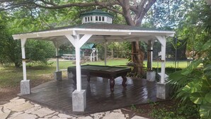Un kiosque doté d’une terrasse en bois, d’une table de billard et d’une petite table.
