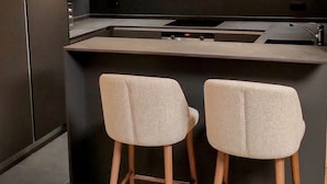 A modern kitchen with a dark countertop, two bar stools, and three pendant lights. - Cosy apartment in Courchevel 1550 (Courchevel)