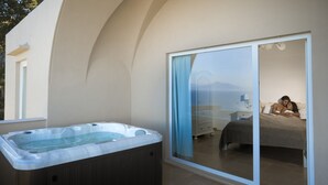 A modern bathroom with a large bathtub, a shower area, and a glass-enclosed bedroom with a bed and a nightstand. - Villa DAlessandro Tatiana private apartment and private hot jacuzzi (Anacapri)