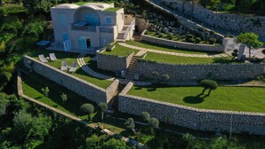A modern villa with a curved roof, a balcony, and a stone retaining wall. - Villa DAlessandro Tatiana private apartment and private hot jacuzzi (Anacapri)