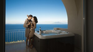 A couple standing by a balcony with a hot tub and a view of the sea. - Villa DAlessandro Tatiana private apartment and private hot jacuzzi (Anacapri)