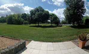 Relax in a serene outdoor space surrounded by lush trees and a beautifully manicured lawn.