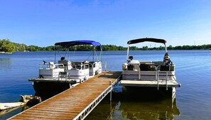 Two boats docked at a wooden pier with a clear view of the water and a distant shoreline. - Swan Lake Resort & Campground - Lakeside Cabin #1 (Fergus Falls)