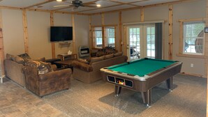 A cozy living room with a pool table, comfortable seating, a television, and a large window. - 5 bedroom home in Paradise!!  4 miles from Tahquamenon Falls (Paradise)