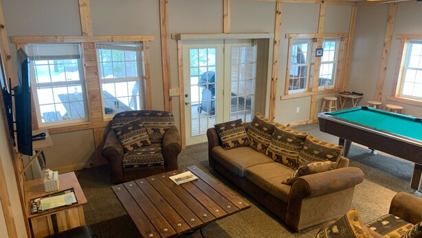 A cozy room with a pool table, two sofas with patterned cushions, a wooden coffee table, and a television. - 5 bedroom home in Paradise!!  4 miles from Tahquamenon Falls (Paradise)